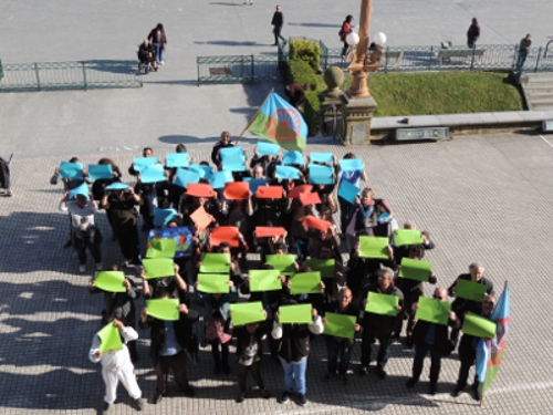 Un grupo forma la bandera gitana con cartones de colores