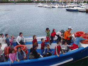 Un grupo de niños subidos en un barco en el puerto